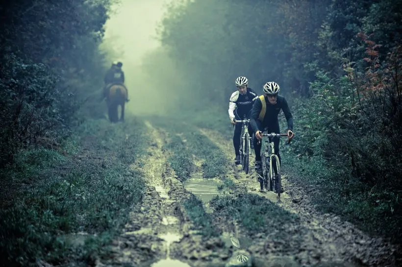 Two cyclists pass a horse on a very muddy stretch of the Ridgeway