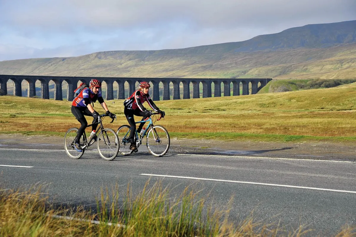 Cyclists with the iconic Ribblehead viaduct on the Settle to Carlisle railway in the background