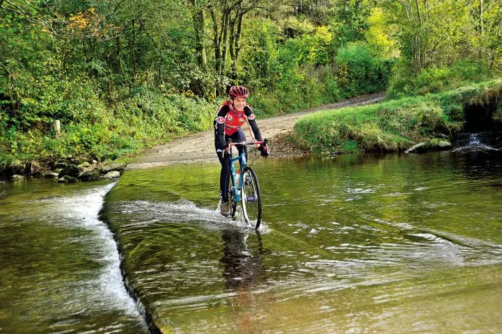 A cyclist rides through a ford in the North of England