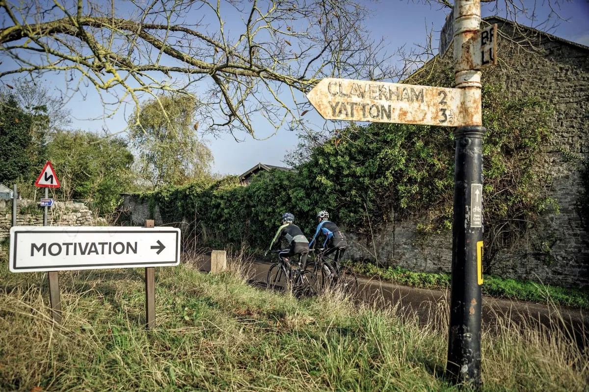 Two cyclists ride past direction signs in Somerset