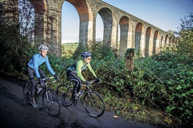 Two cyclists ride past Pensford Viaduct near Bristol
