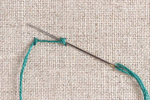 Needle and thread demonstrating ladder stitch