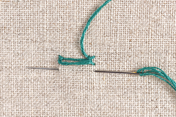 Needle and thread demonstrating ladder stitch