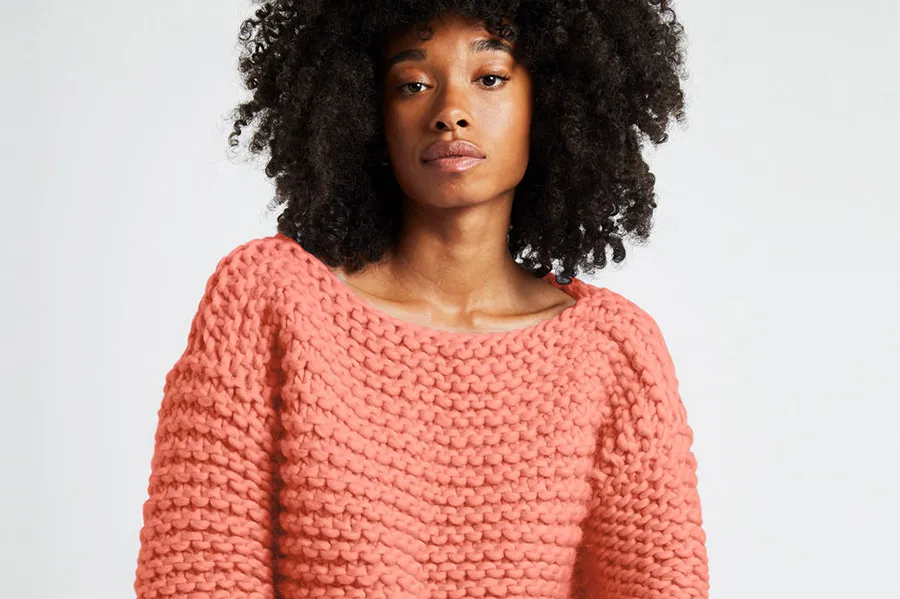Lady in a chunky knitted peach jumper made using Wool and the gang Knitting for beginners kit