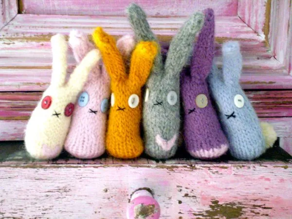 A group of different coloured knitted easter bunnies with button eyes