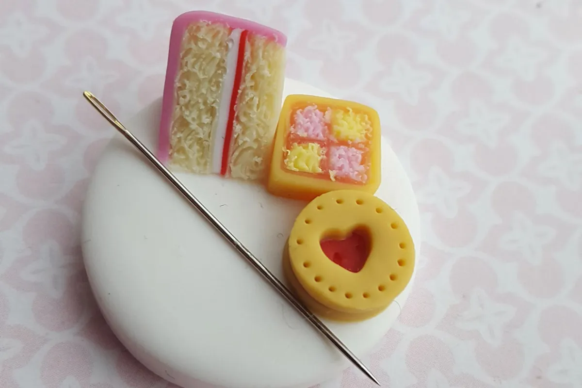 Polymer clay needle minders shaped like cake slices and a jammy biscuit.