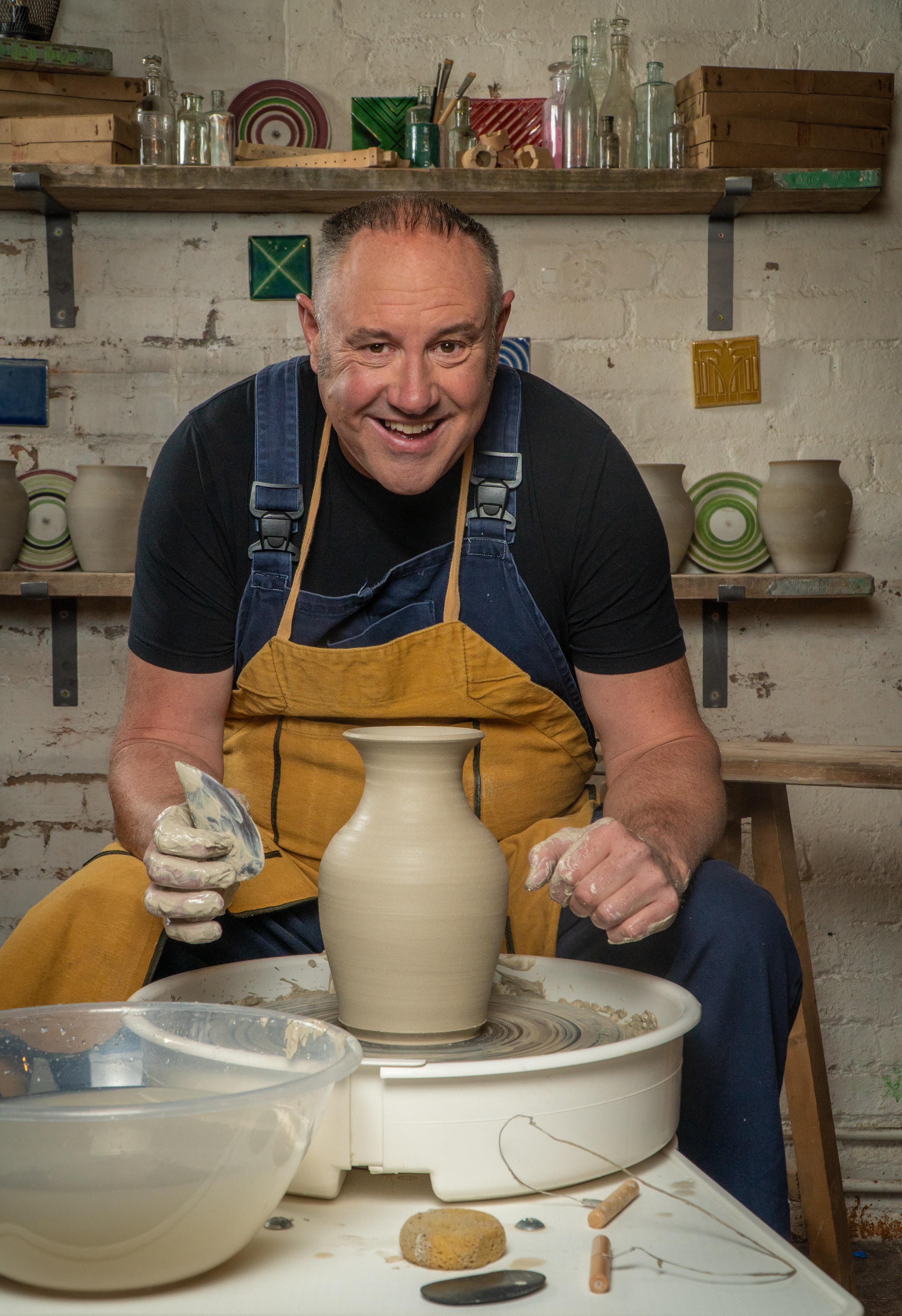 potter professional happy man working with brown clay in workshop