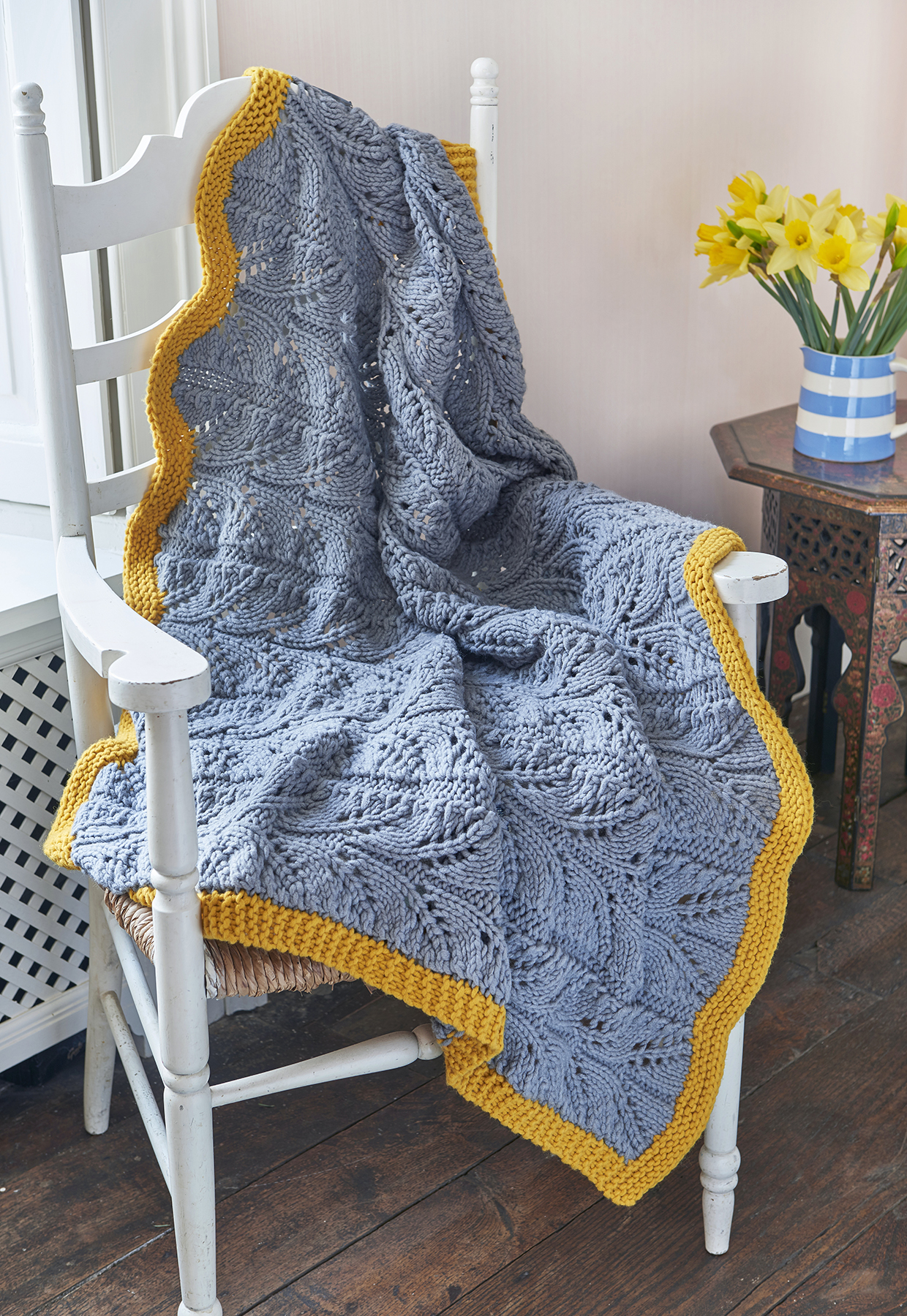 a blue and yellow lace blanket is thrown over the seat and back of a chair