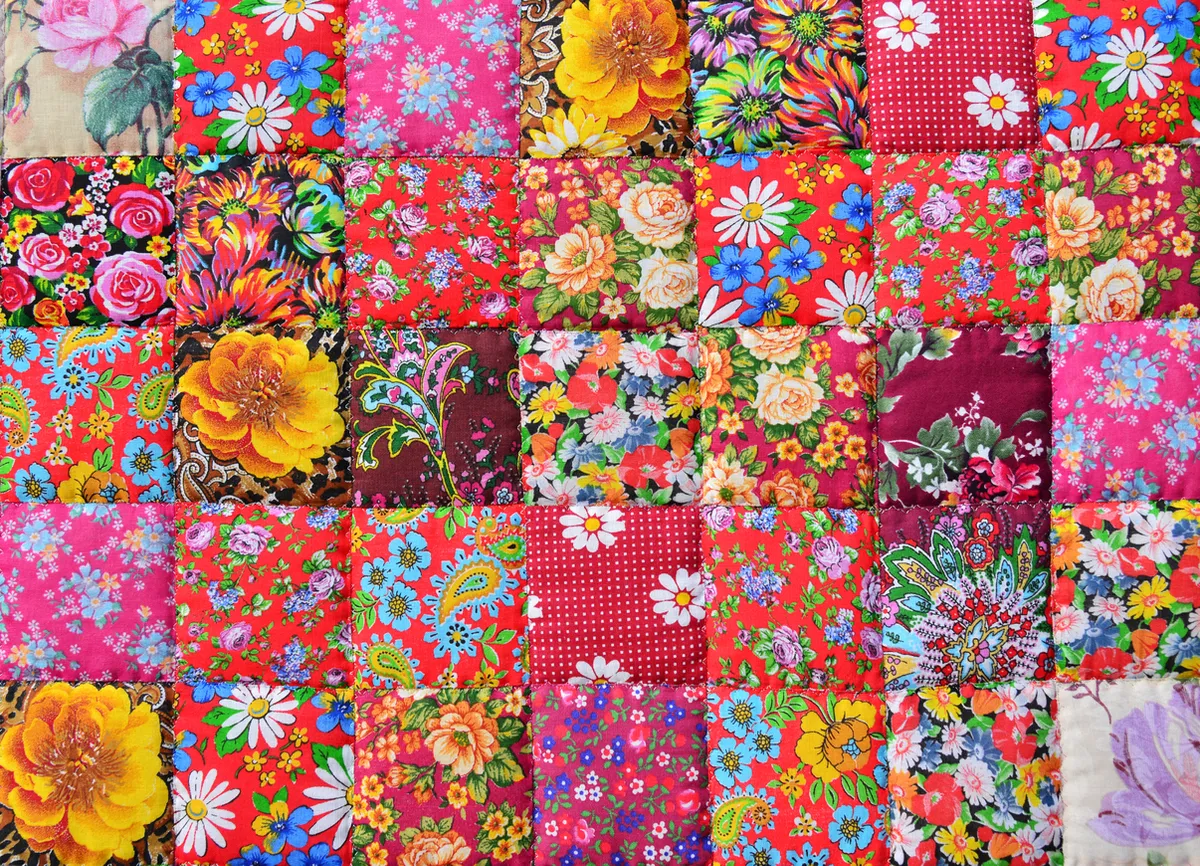 Handmade Patchwork quilt with flower print as background. Retro Style Handmade Blanket Or Cloth Wallpaper