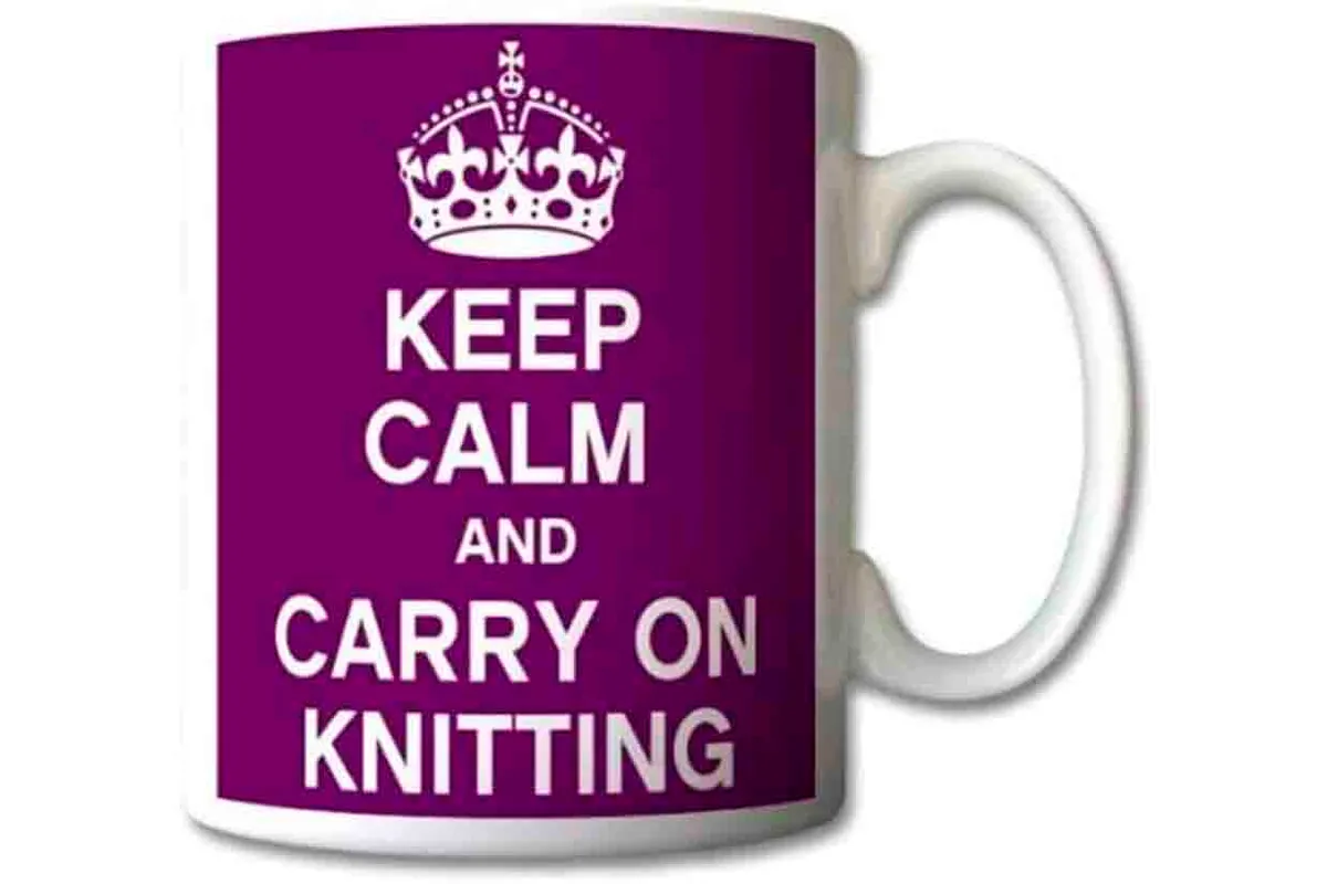 The white mug has a purple solid print with white text saying keep calm and carry on knitting