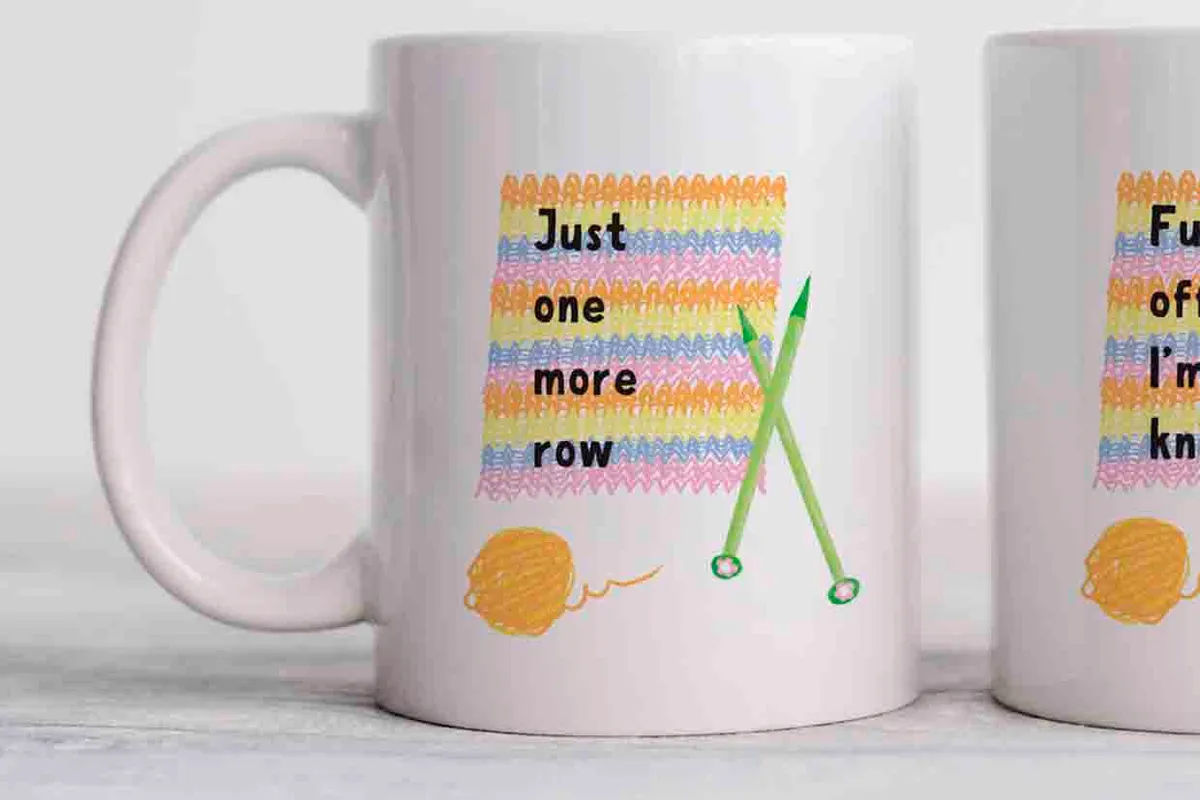 this mug is white with a colourful row of pastel striped knitting alongside green needles, a green ball of yarn and black wording that says just one more row