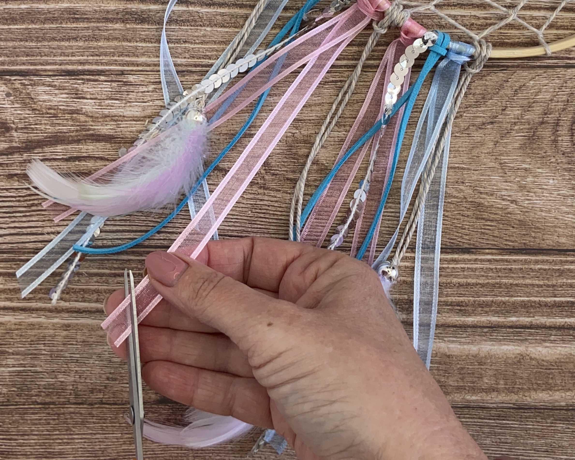 hand trimming to end of ribbon at bottom of dreamcatcher
