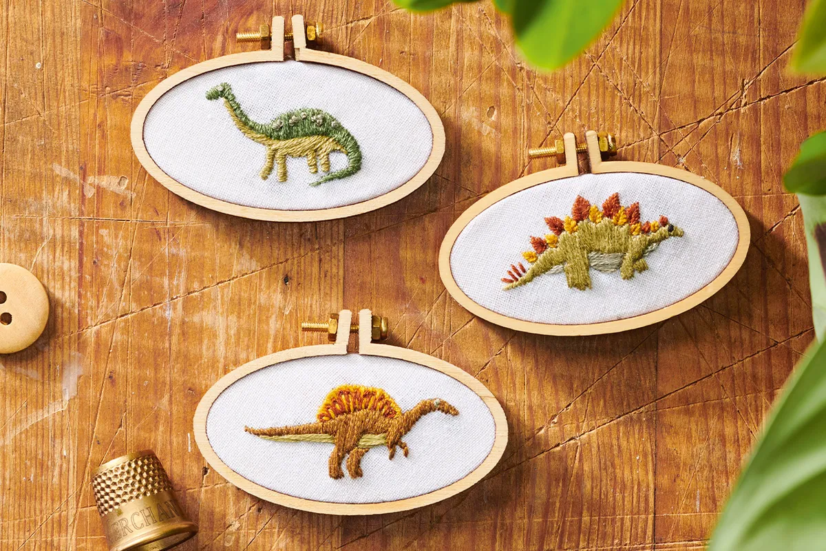 a trio of dinosaur embroidery hoops