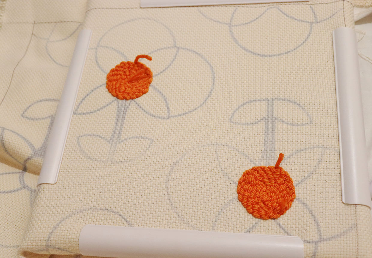 Punching the centres of the flowers using orange yarn