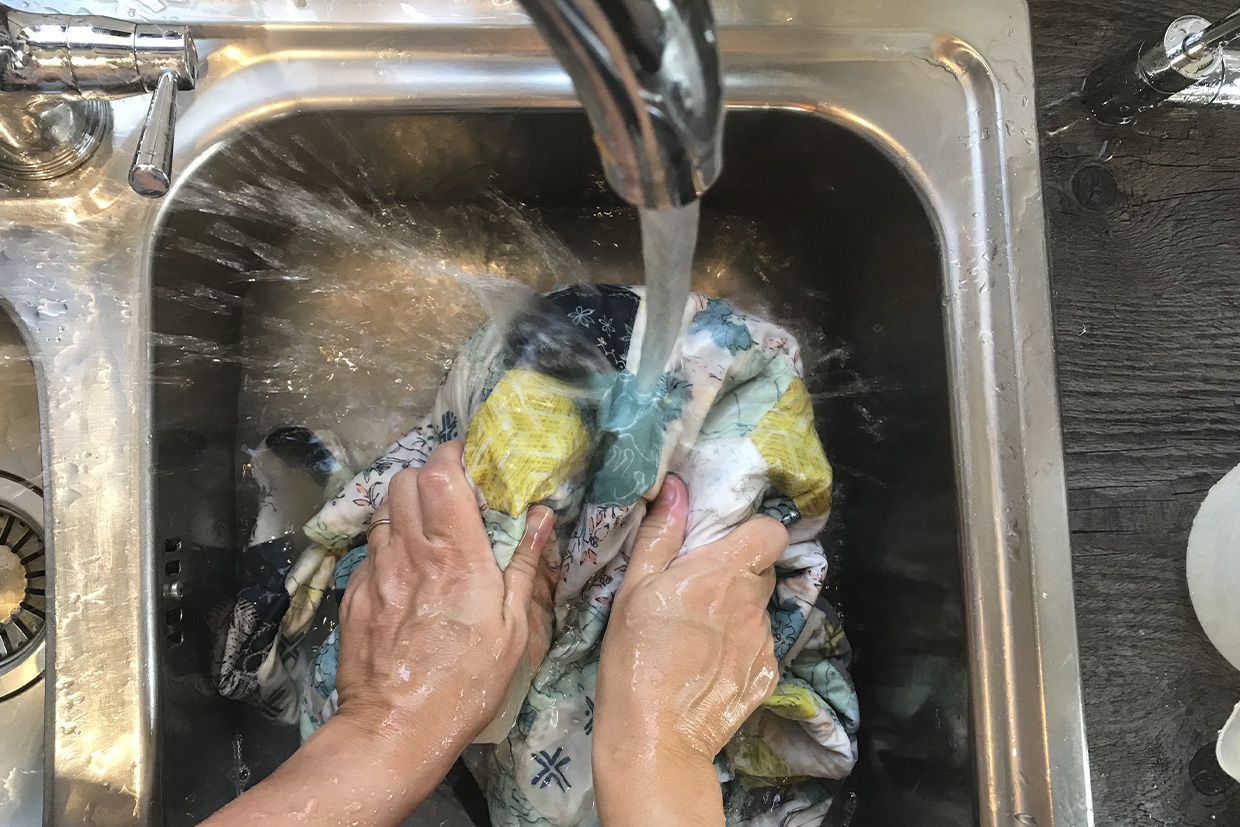 Hand rinsing a quilt in a kitchen sink to wash it