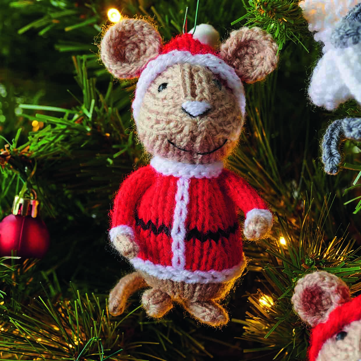 You can see the whole of the santa mouse hanging atom a chtosymas tree, with his knitted santa suit and hat and hit white embroidered nose with black embroidered outline and smiling embroidered mouth