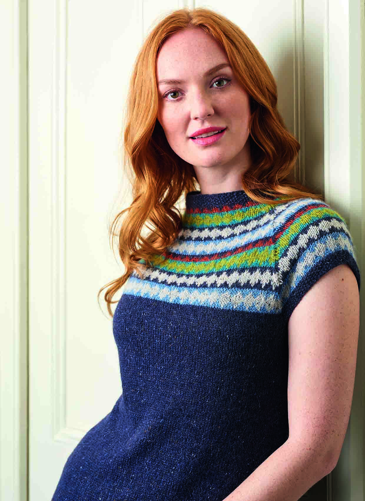 Redhaired model whose name is sylvia looks seriously into he camera, you can see the detail of the colour work yoke on the knitted dress pattern she is modelling