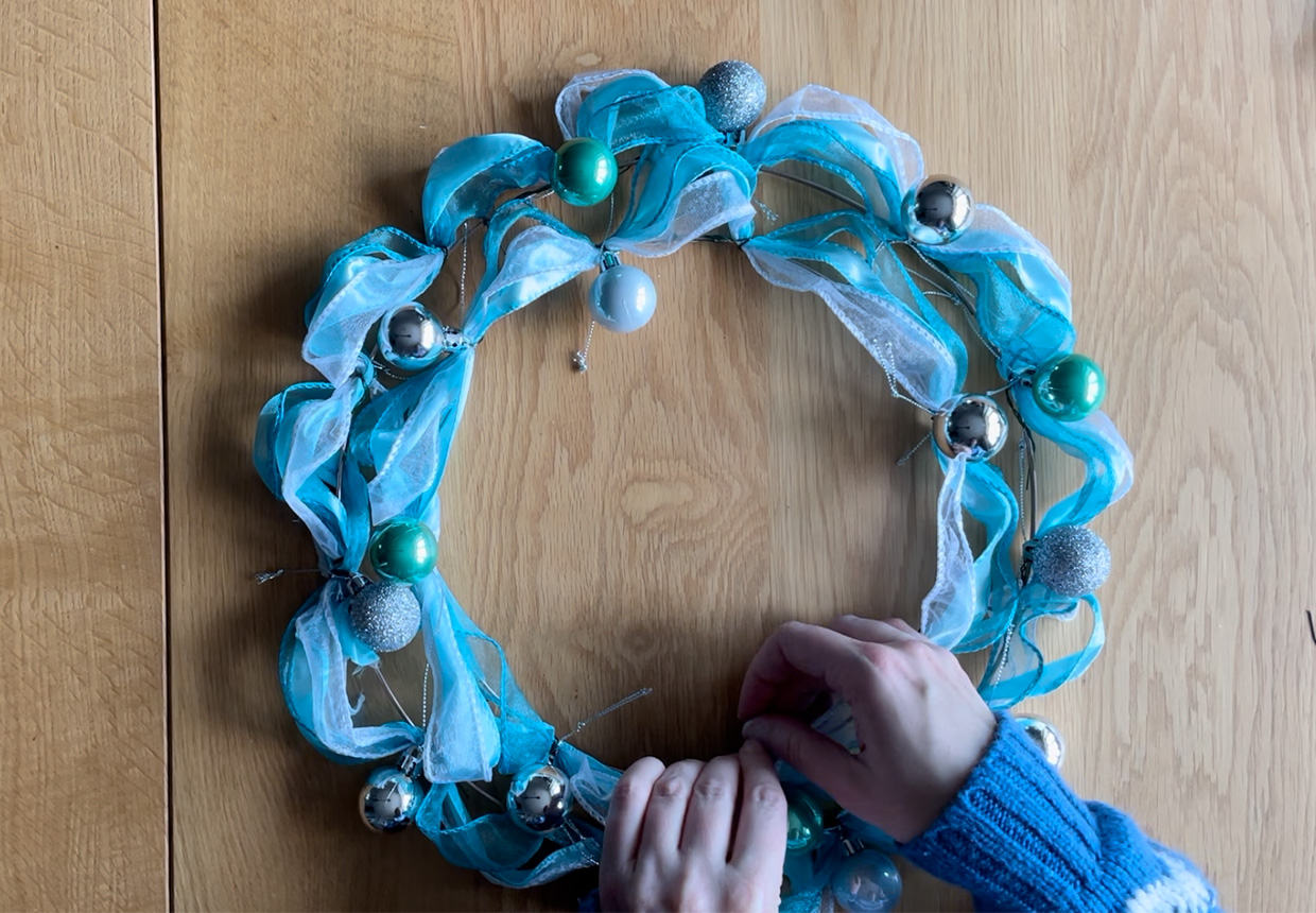 Adding baubles to the ribbon wreath