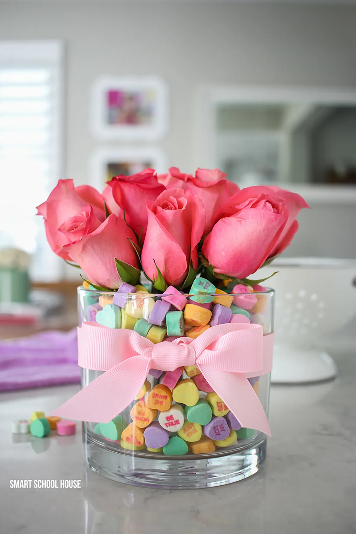 A vase filled with pink roses and love heart sweets