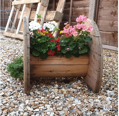 Wooden cable spool upcycled into a garden planter bursting with blooms