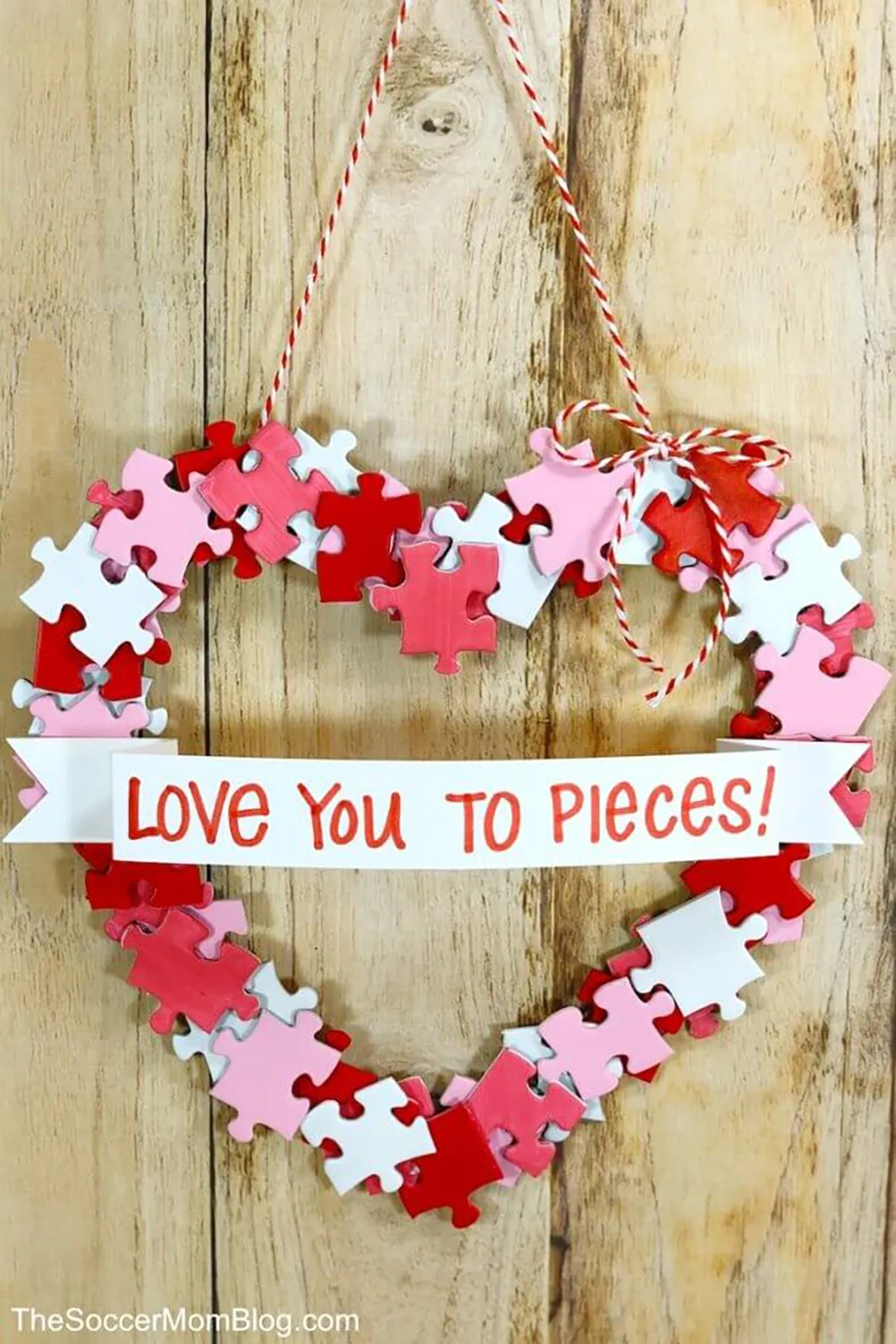 diy valentines decorations - puzzle wreath hanging against a wooden wall
