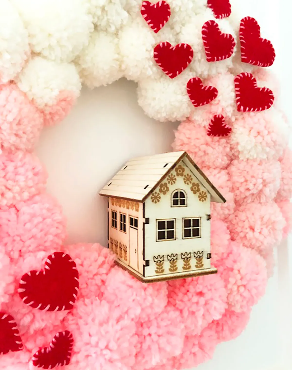 diy valentines decorations - wreath made of pom poms with a small wooden house