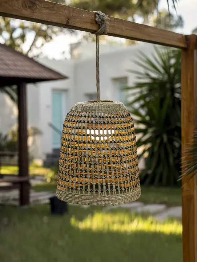 A rattan pendant light hanging from a beam in the garden
