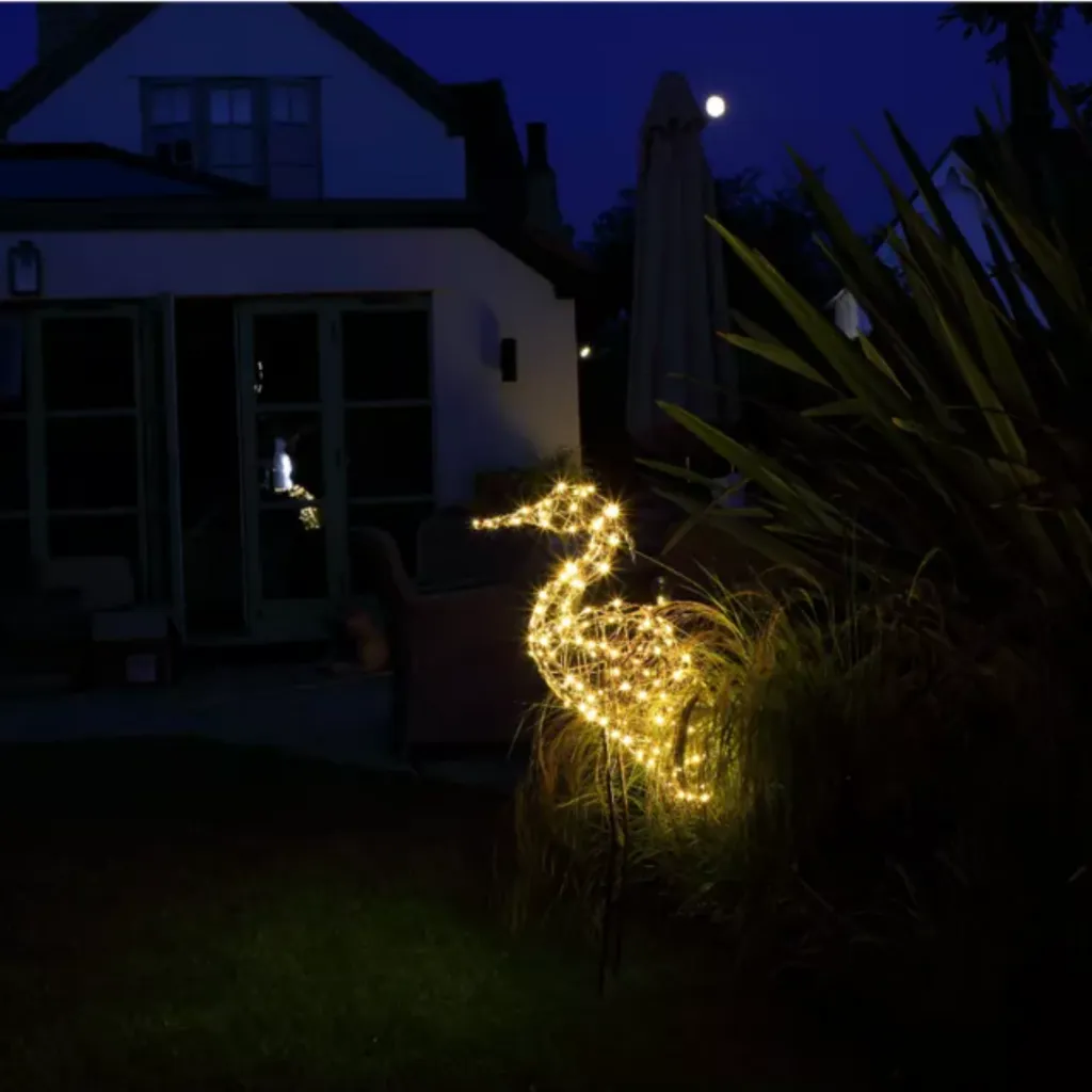 Wicker heron lit up in a garden at night