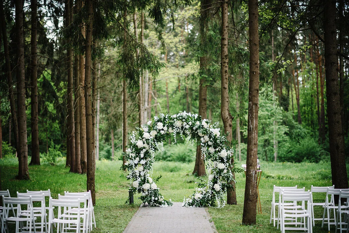 A DIY floral wedding arch at a backyard wedding in a forest