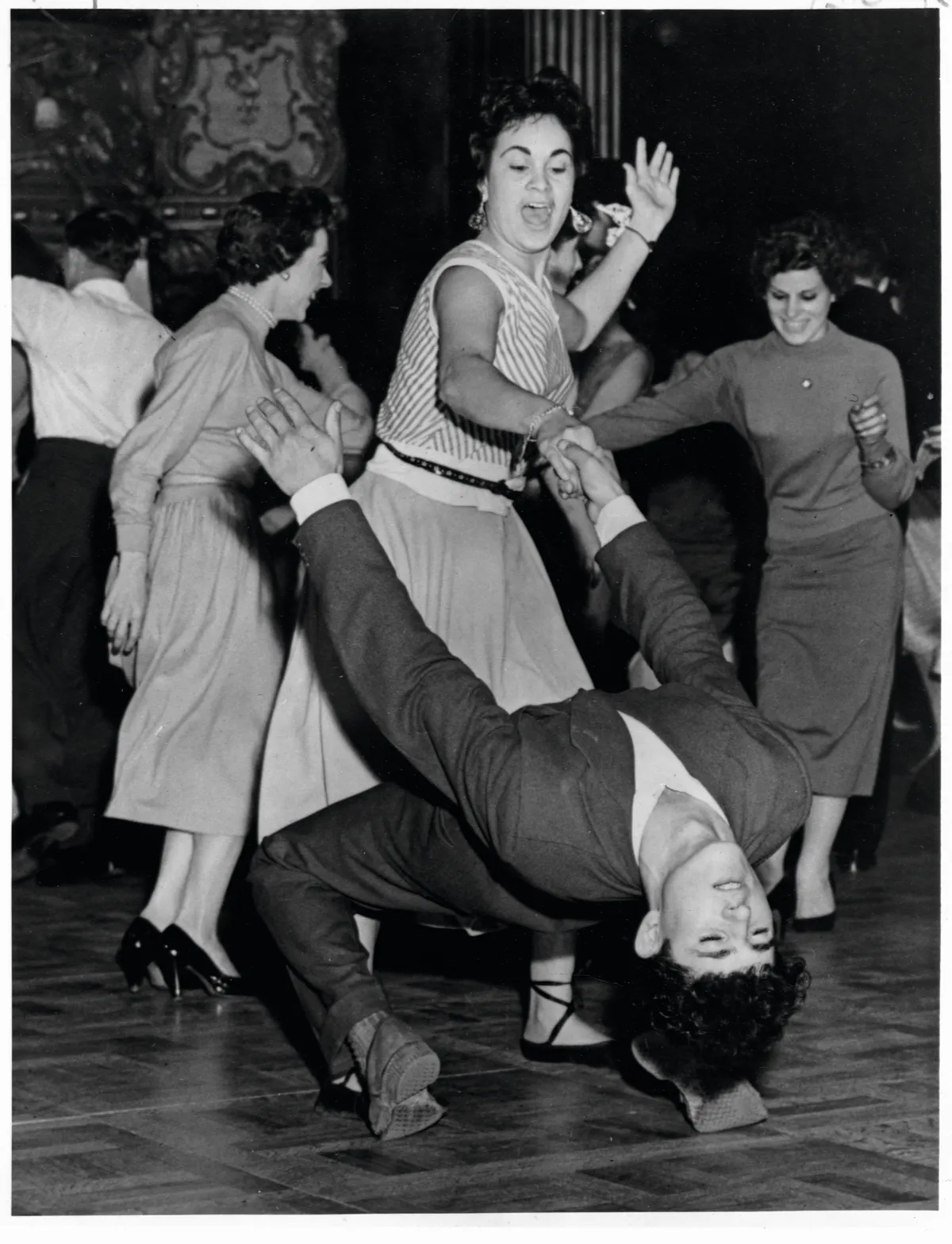 A woman holds a man by his hand as he dips down on the crowded dance floor at the London Dance Hall. | Location: London Dance Hall, London, England, UK. (Photo by Library of Congress/Corbis/VCG via Getty Images)