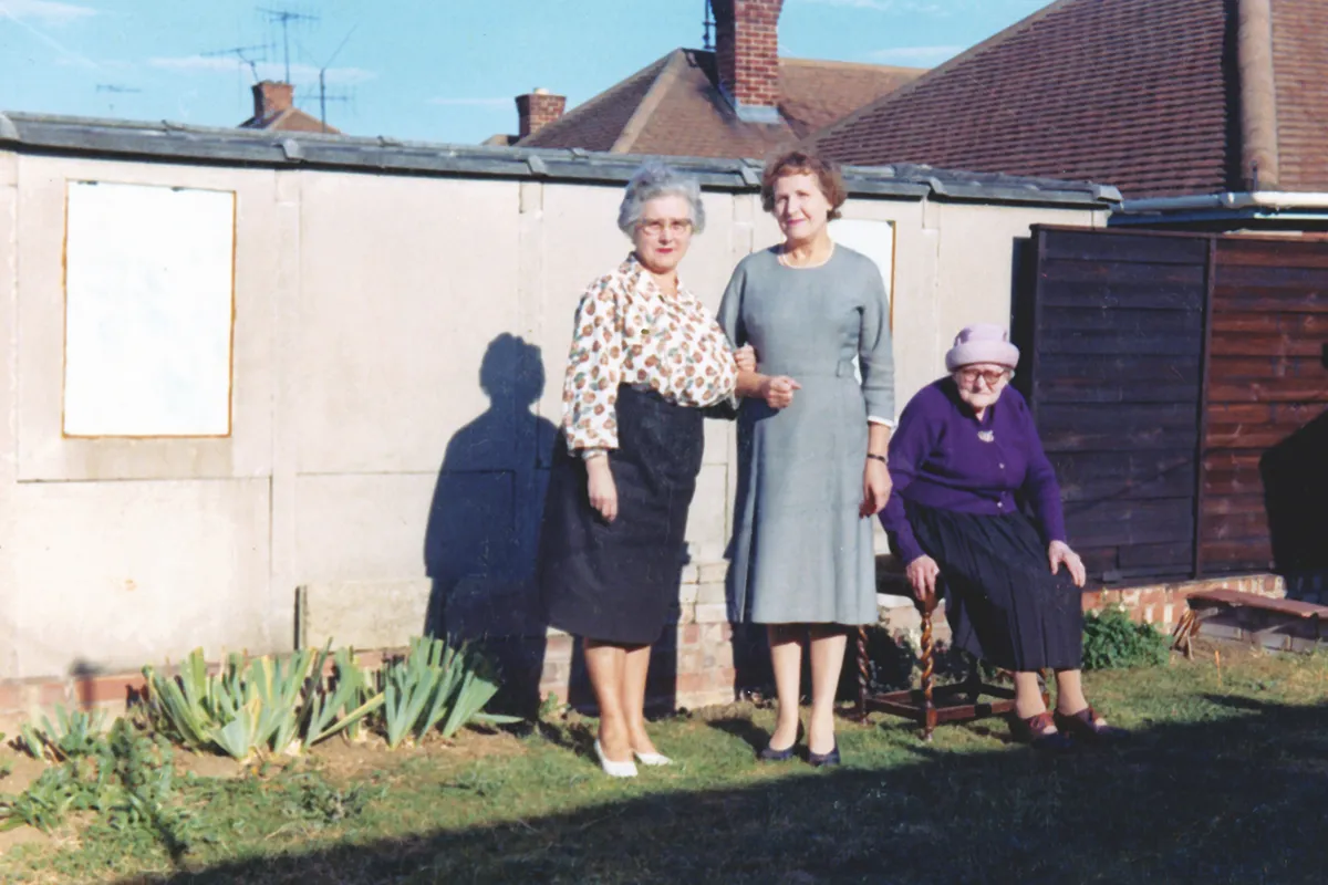 A colour photograph of three old women in a back garden