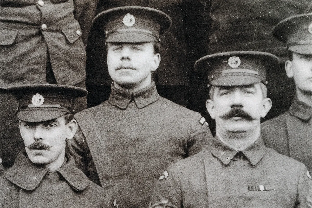 Black and white photograph of the faces of three men in military uniform. The one on the right has a moustache.