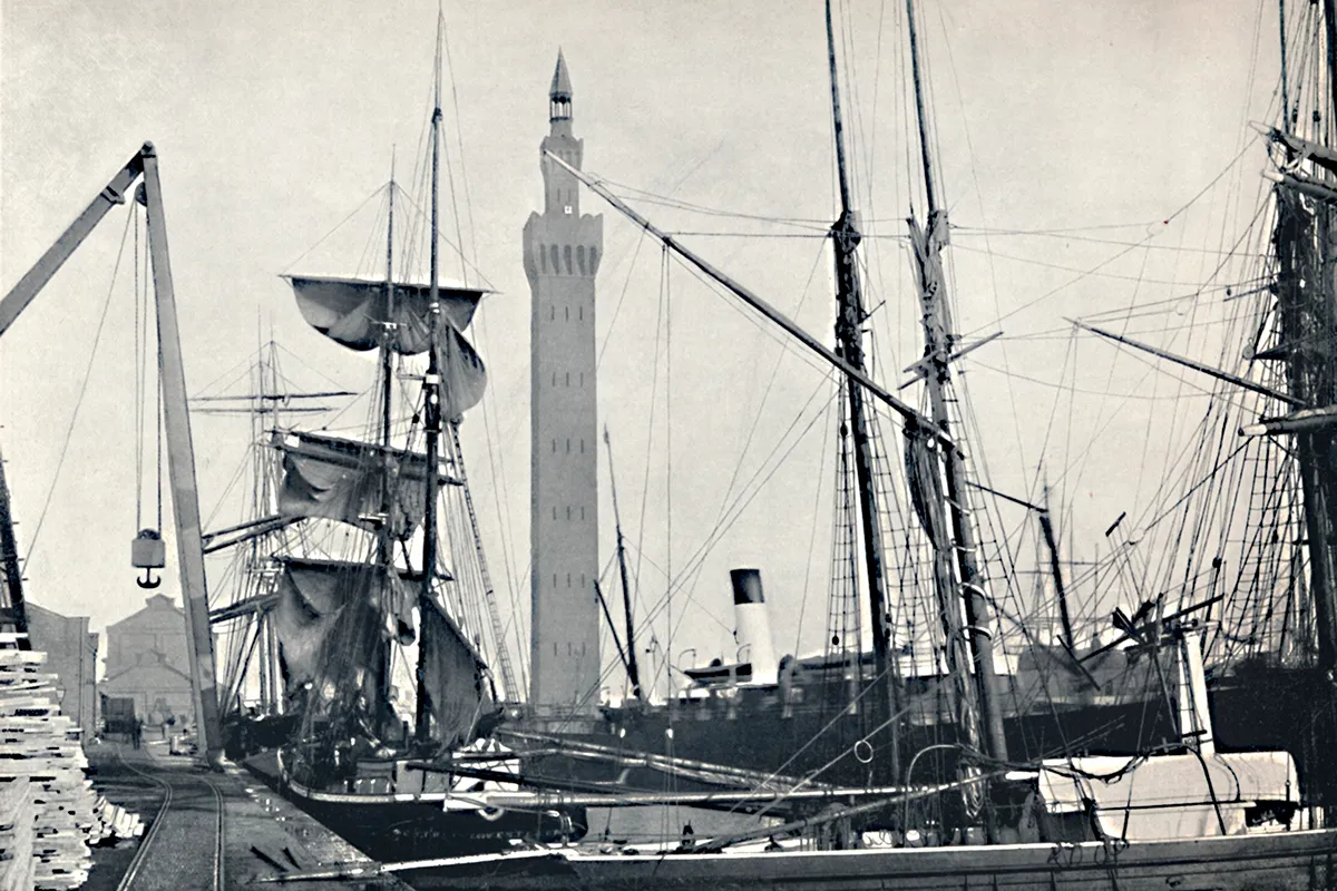 Black and white photograph of the masts, sails and funnels of ships at a dock