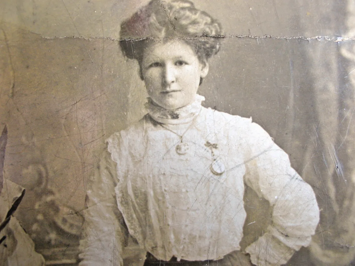 Black and white photograph of a woman with her hair pinned up wearing an old-fashioned white blouse.