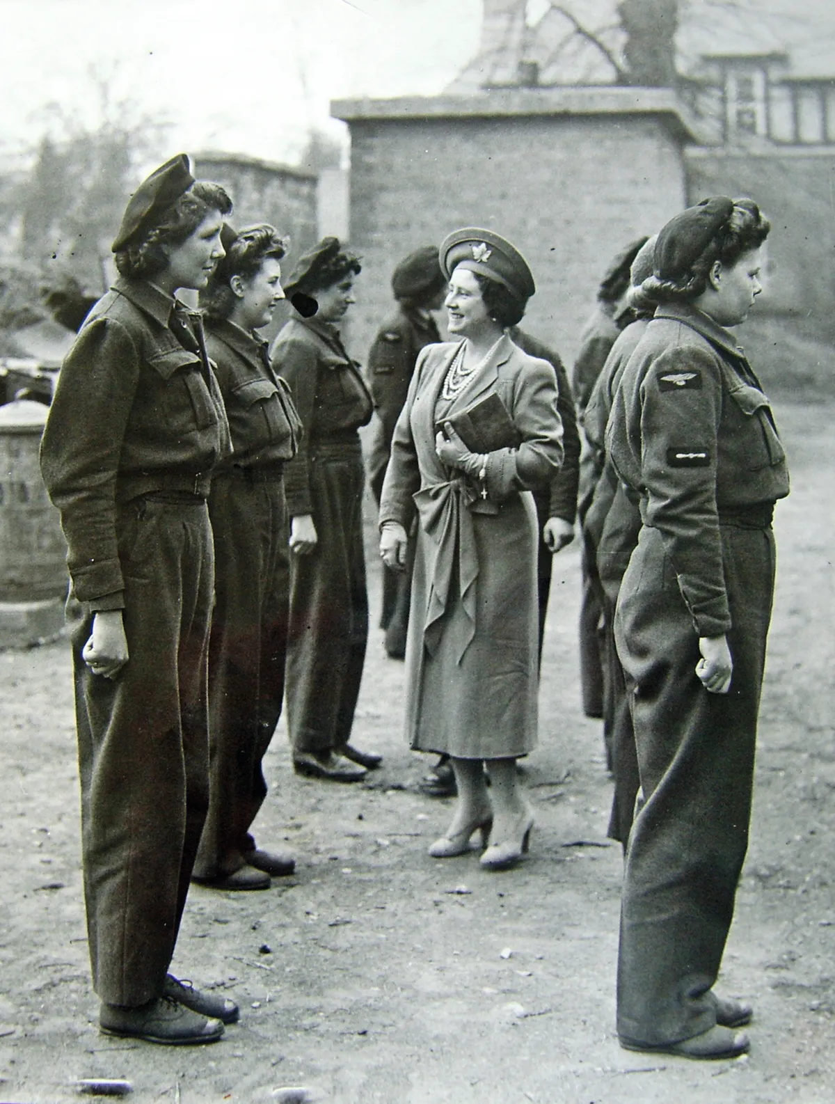 Black and white photograph of Queen Elizabeth inspecting a row of women in airforce jumpsuits during the Second World War