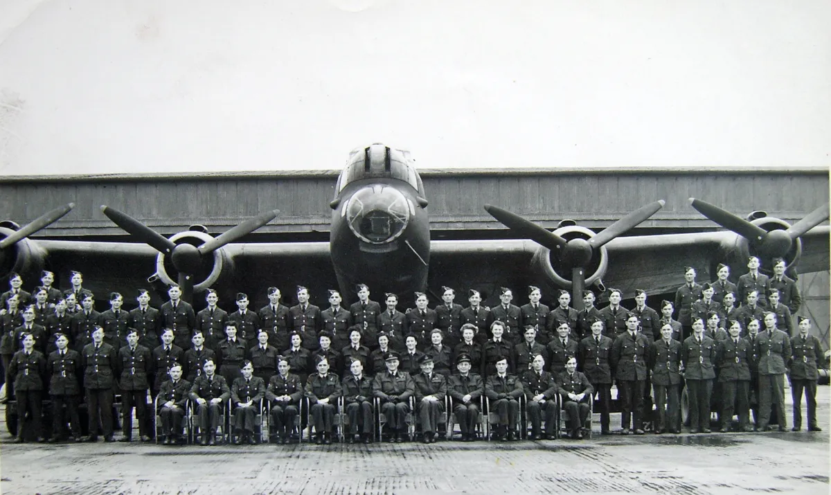 Black and white photograph of a group of men and women in uniform standing in front of a large plane