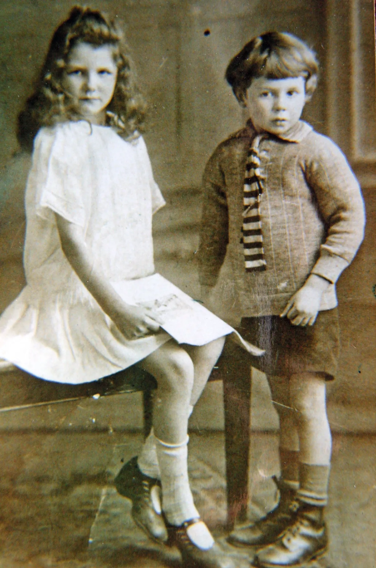 A black and white photograph of a young boy and girl in old-fashioned clothes