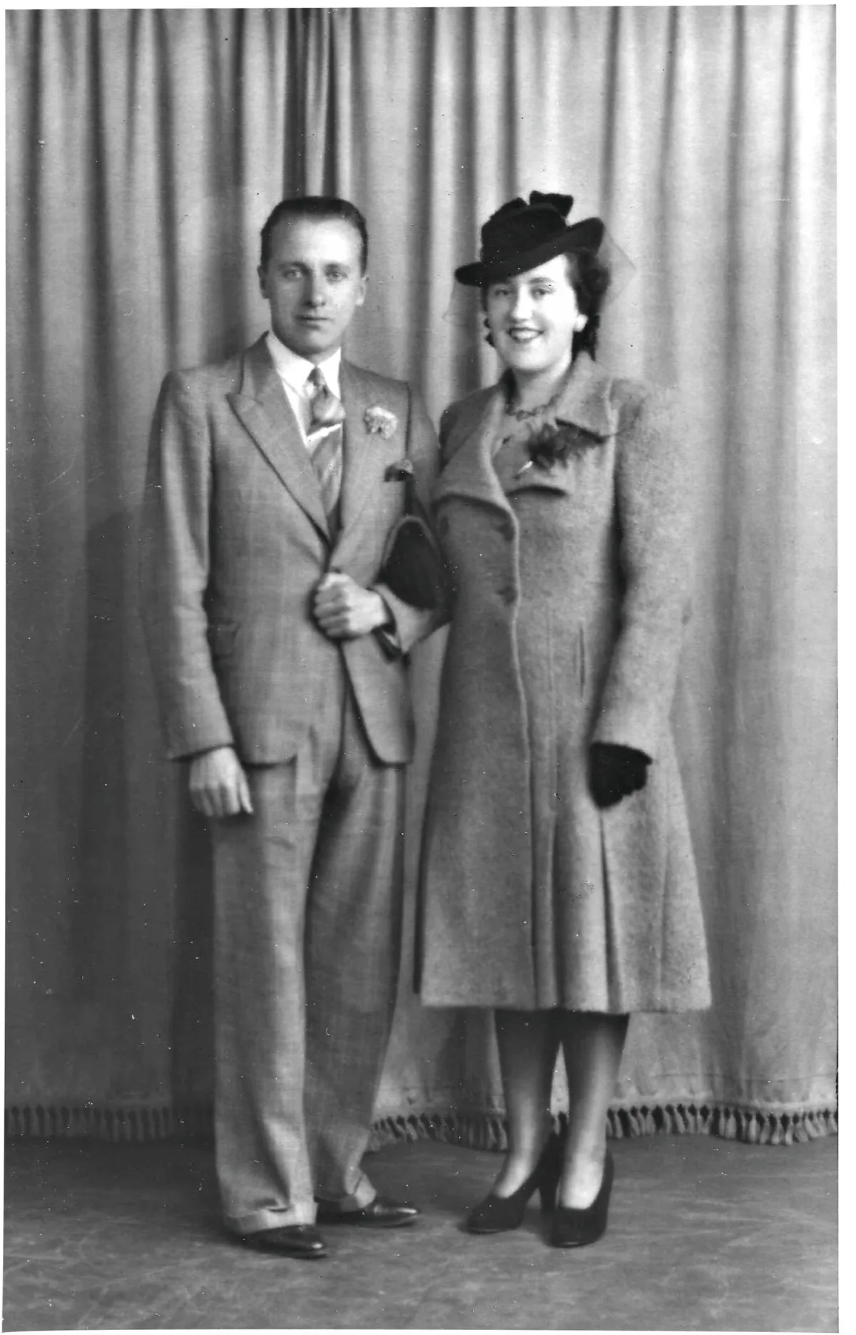 Black and white photograph of a man wearing a suit and a woman wearing a hat with a veil posing for their wedding