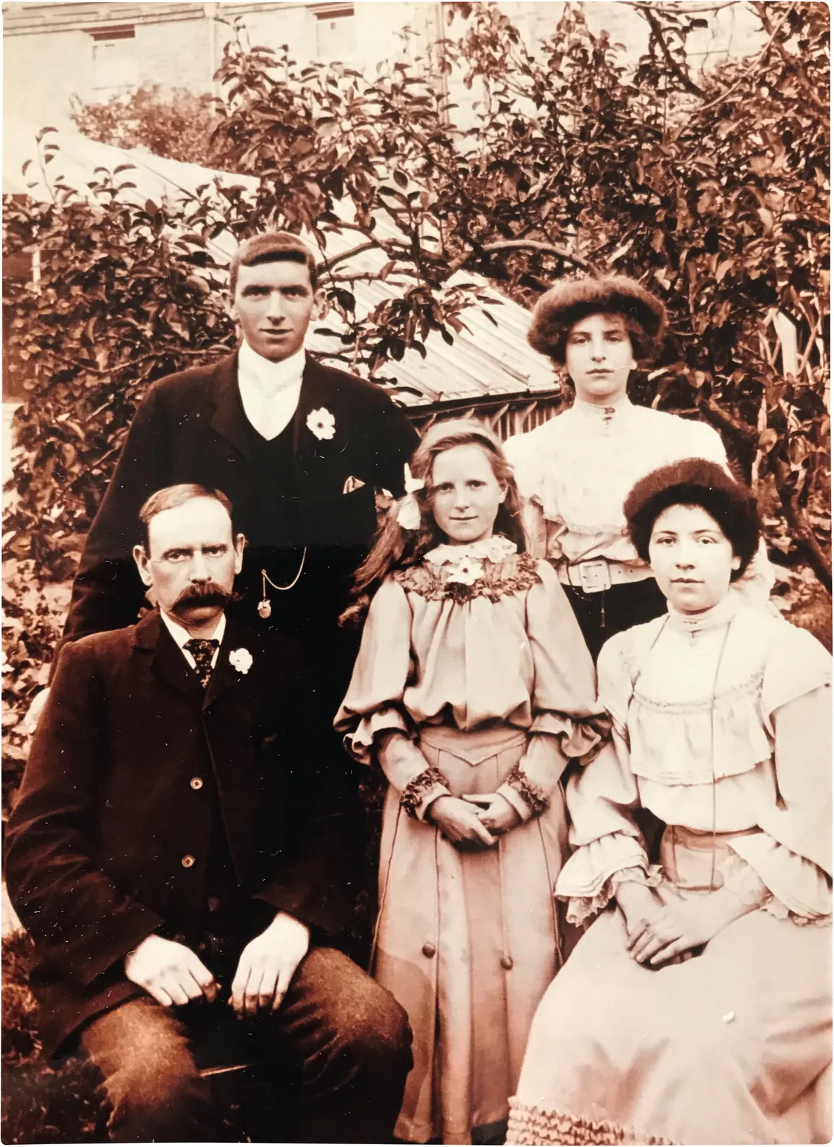 Black and white photograph of a little girl, a middle-aged man, two young women and a young man in Edwardian dress