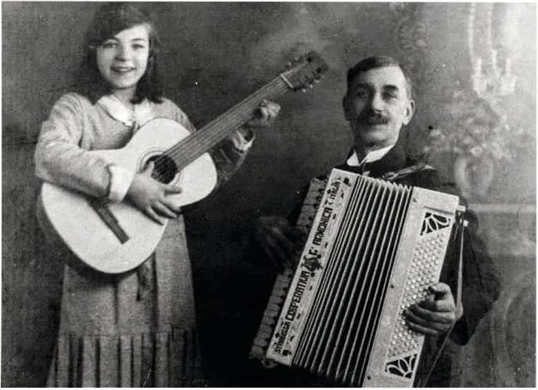 Black and white photograph of a little girl playing the guitar and a man playing an accordion.