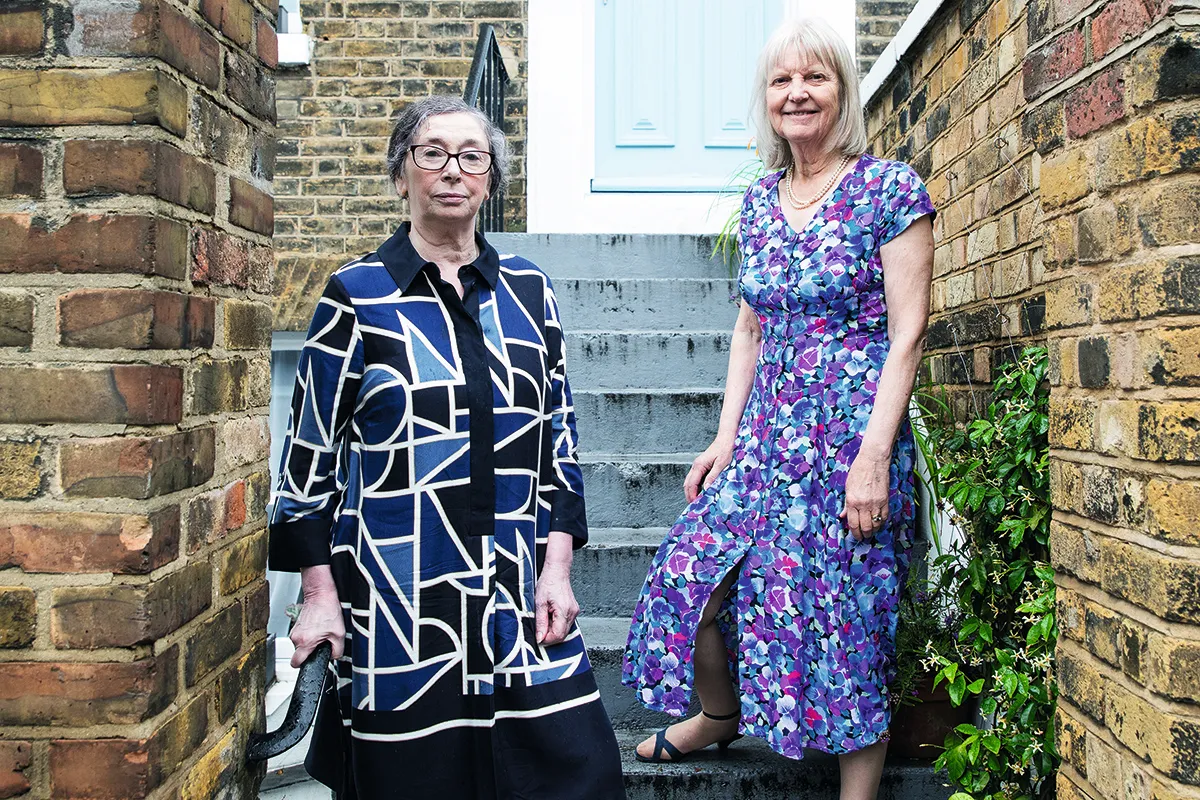 Colour photograph of two middle-aged women standing on the steps of a house