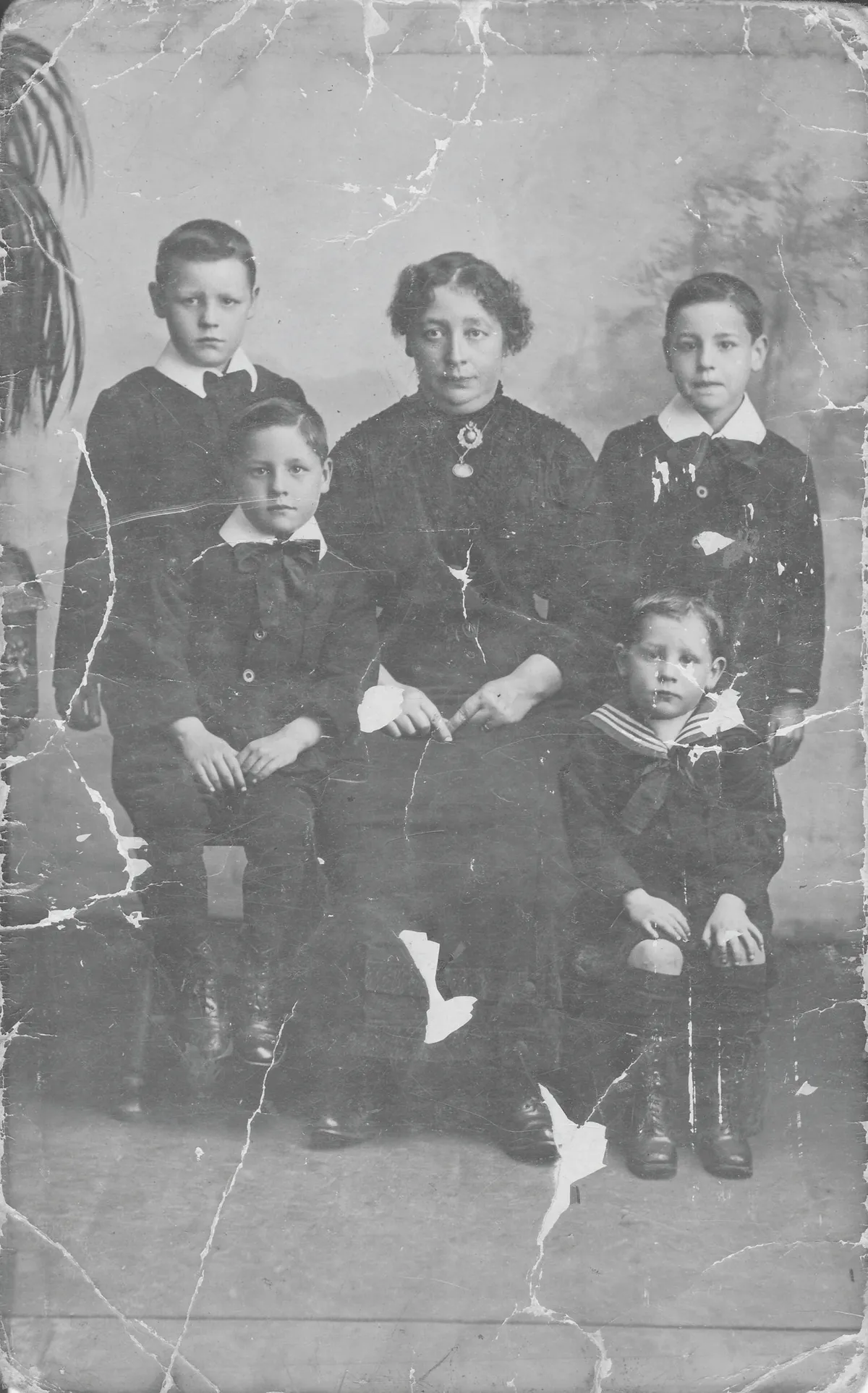 Black and white photograph of a woman and four little boys in mourning clothes
