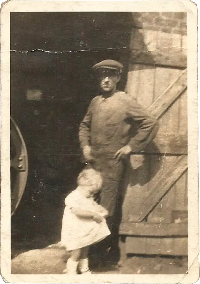 Black and white photograph of a man in a flat cap and a toddler in a white dress