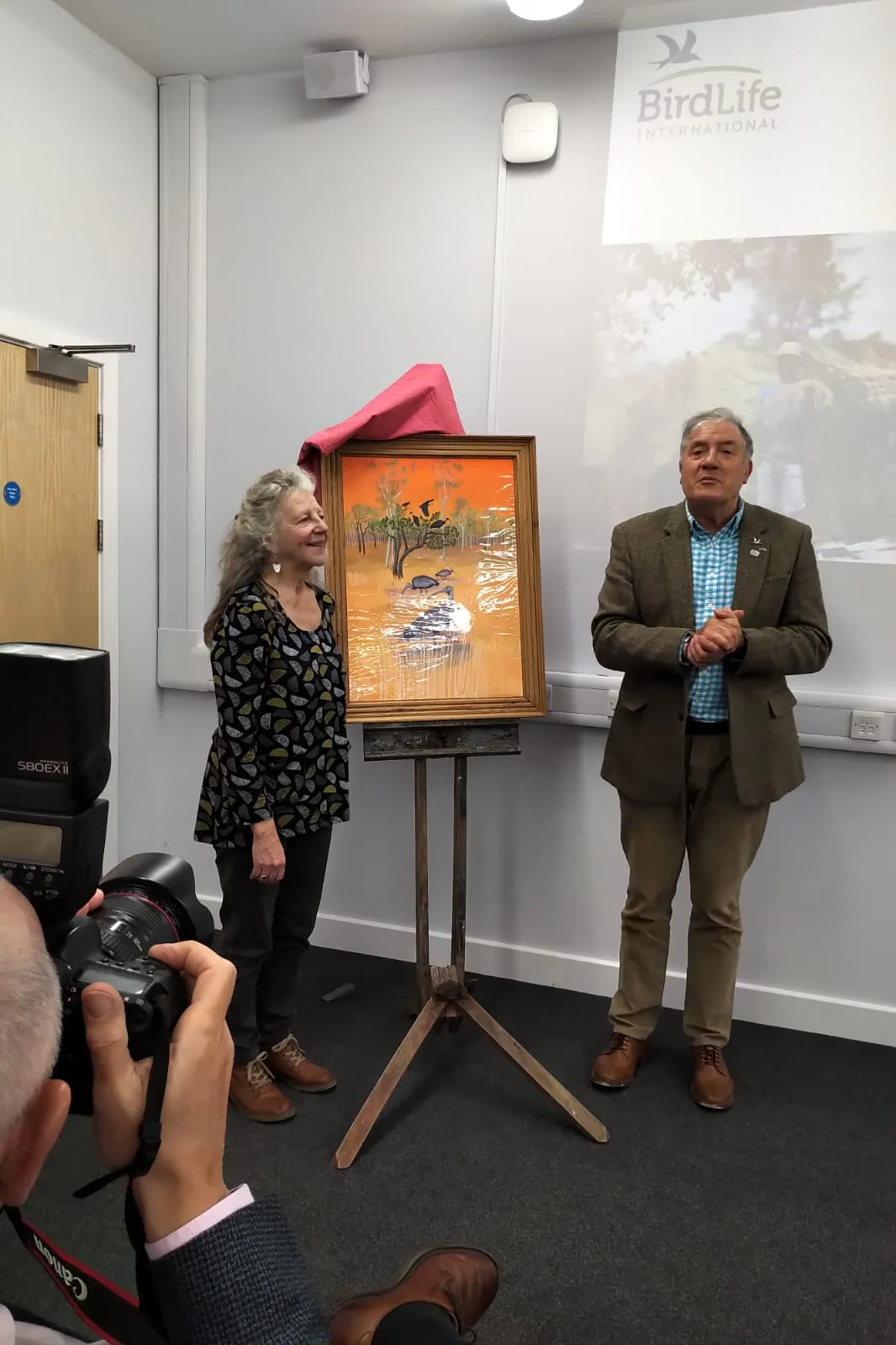 Wildlife artists Carrie Aykroyd and Birdfair founder Tim Appleton with the poster for Birdfair 2019.
