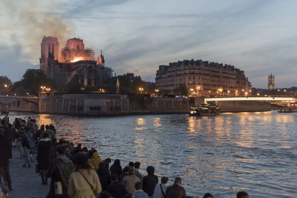 People watch as fire and smoke rise from a fire at Notre-Dame Cathedral. © Martin Barzilai/Bloomberg/Getty