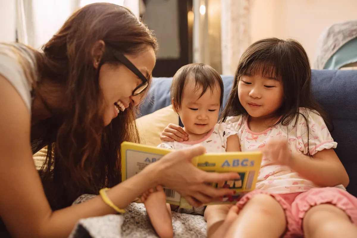 Mother reading a story book to her children.