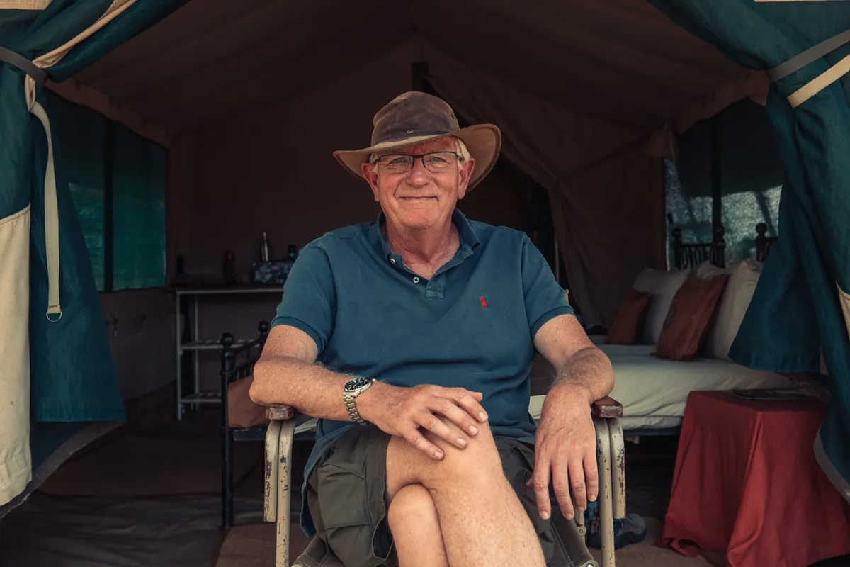 Keith sits in front of a safari tent.