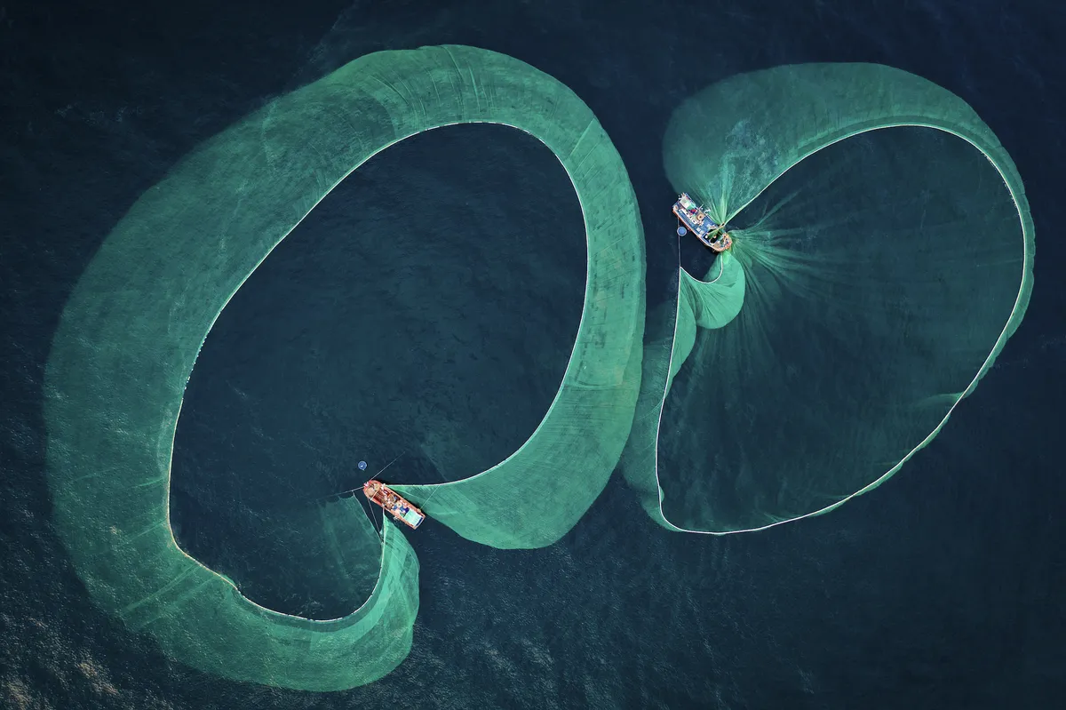 Two fishing boats cast out their nets