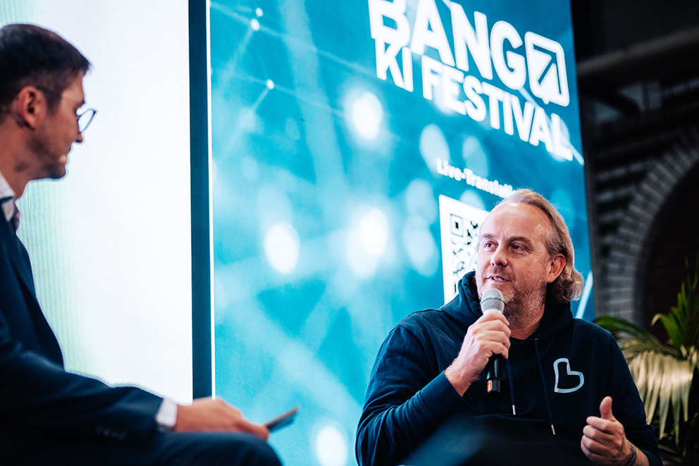 Niels Battenfeld wird auf der Bühne beim BIG BANG KI FESTIVAL 2026 interviewt zu KI Hotelbuchung