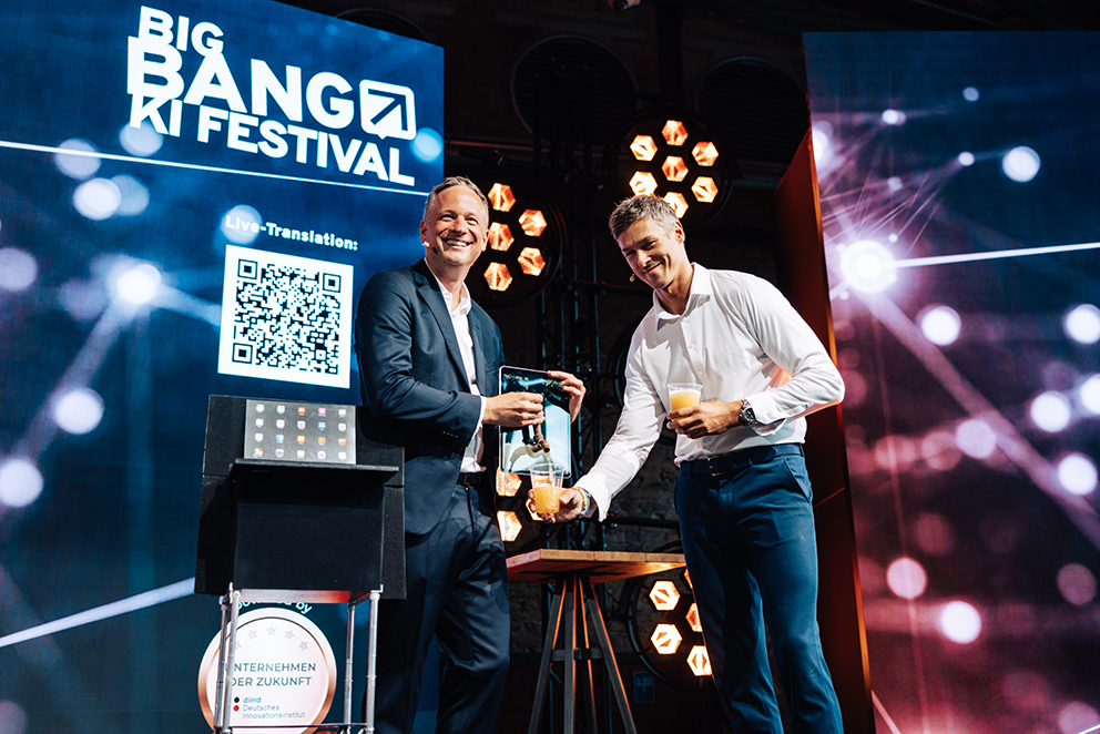 Der KI Magier Simon Pierro zapft Bier aus einem Tablet auf der Bühne des BIG BANG KI FESTIVALS 2026